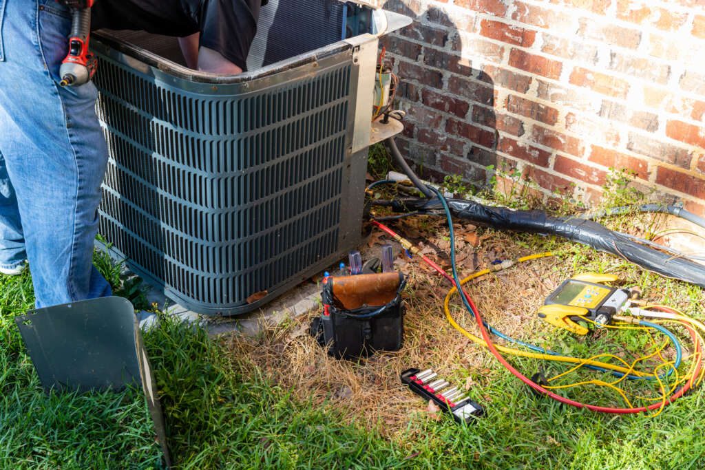 AC Technician working on an outdoor ground AC unit.